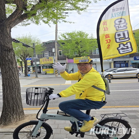 자전거를 타고 시민들과 인사하는 윤민섭 춘천시의원 후보.