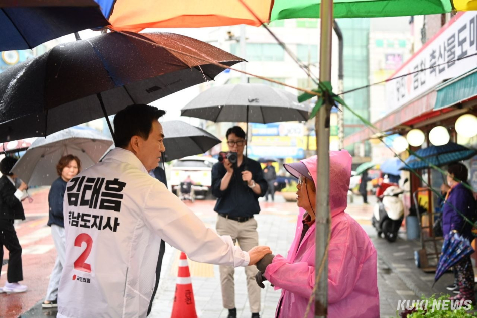 김태흠 충남도지사 후보가 20일 비가 오는 가운데에서 당진 시장을 방문해 지역주민들과 소통하고 있다.