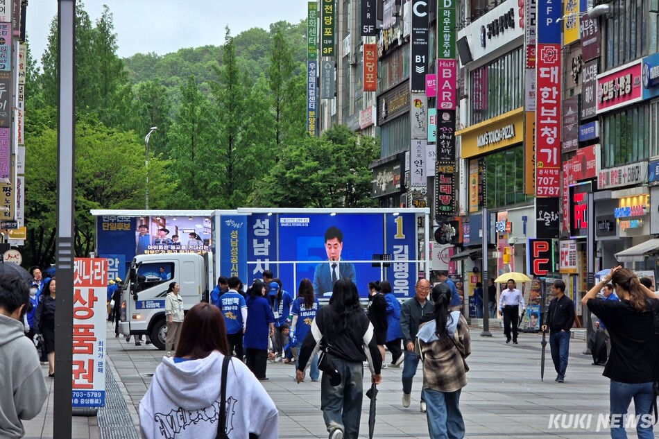 출근하는 시민들이 21일 성남 분당구 서현역 5번출구 김병욱 더불어민주당 성남시장 후보 선거 유세 현장을 보며 지나가고 있다. 김건주 기자
