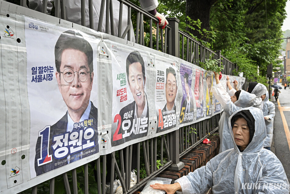제9회 전국동시지방선거 공식 선거운동 첫날인 21일 서울 종로구 예술가의 집 담장에 서울시 선관위 관계자들이 선거벽보를 첩부하고 있다.