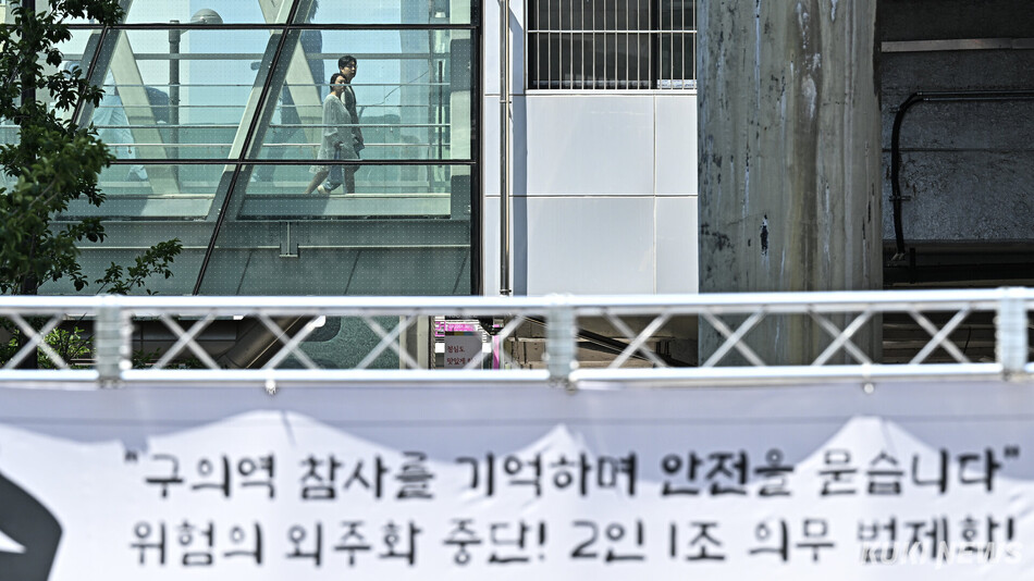 22일 서울 광진구 구의역 인근에서 열린 구의역 참사 10주기 추모문화제 현장 뒤로 시민들이 보행 통로를 지나고 있다