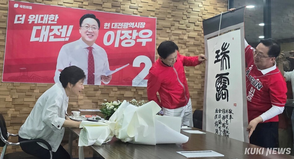 박근혜 전 대통령이 ‘서로‘(상서로울 서, 이슬 로)라는 글씨가 적힌 족자를 이장우 대전시장 후보에게 선물해 이를 펼쳐 보이고 있다. 사진=명정삼 기자