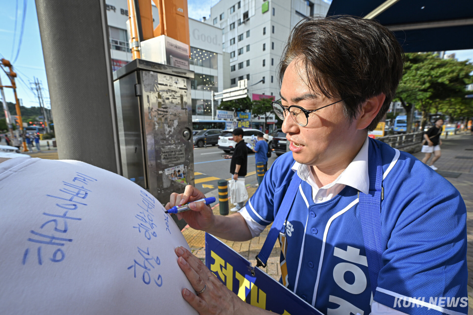 하정우 더불어민주당 부산 북구갑 국회의원 보궐선거 후보가 30일 부산 북구 숙등교차로에서 한 지지자의 상의에 사인하고 있다.