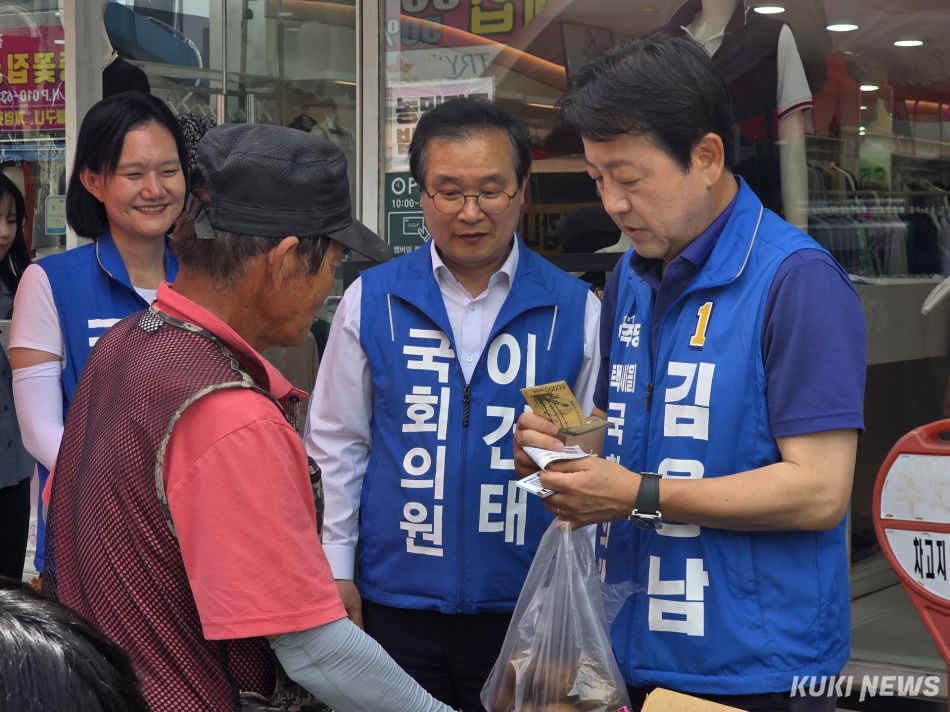 경기 평택을 국회의원 재선거에 출마하는 김용남 더불어민주당 후보가 안중시장 상인에게 안부를 물으며 과일을 사고 있다. 김미경 기자