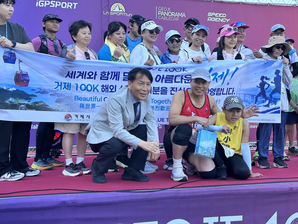 거제 100K 트레일러닝대회 외국인 참가자들이 기념사진을 촬영하고 있다. 앞줄에 호천정씨와 아들 호포언군이 앉아 있다. 거제시 제공