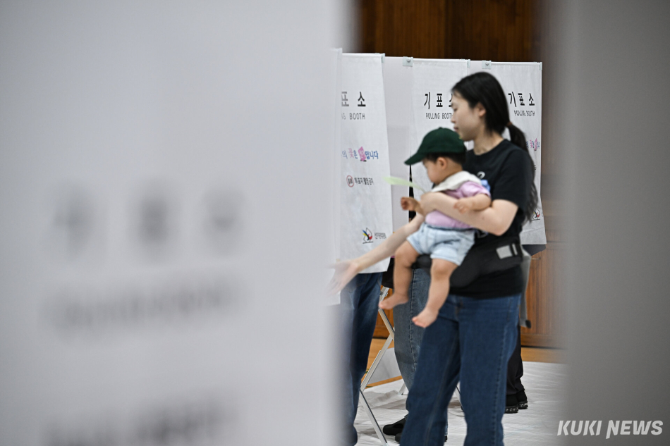 제9회 전국동시지방선거 본투표일인 3일 서울 동작구 본동초등학교 강당에 마련된 투표소에서 한 시민이 아기와 함께 소중한 한 표를 행사하고 있다.
