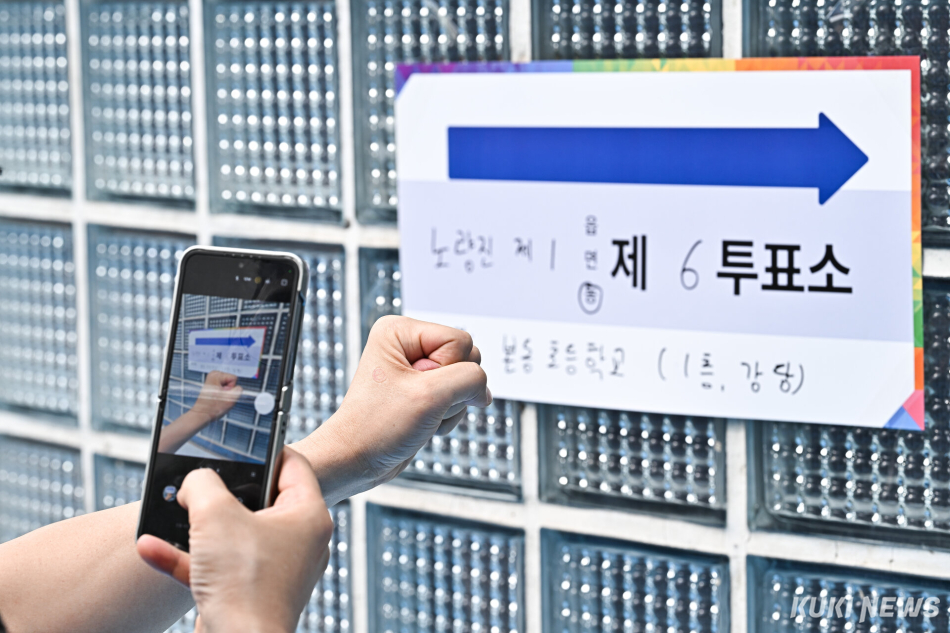 제9회 전국동시지방선거 본투표일인 3일 서울 동작구 본동초등학교 강당에 마련된 투표소에서 한 시민이 투표 인증샷을 촬영하고 있다.