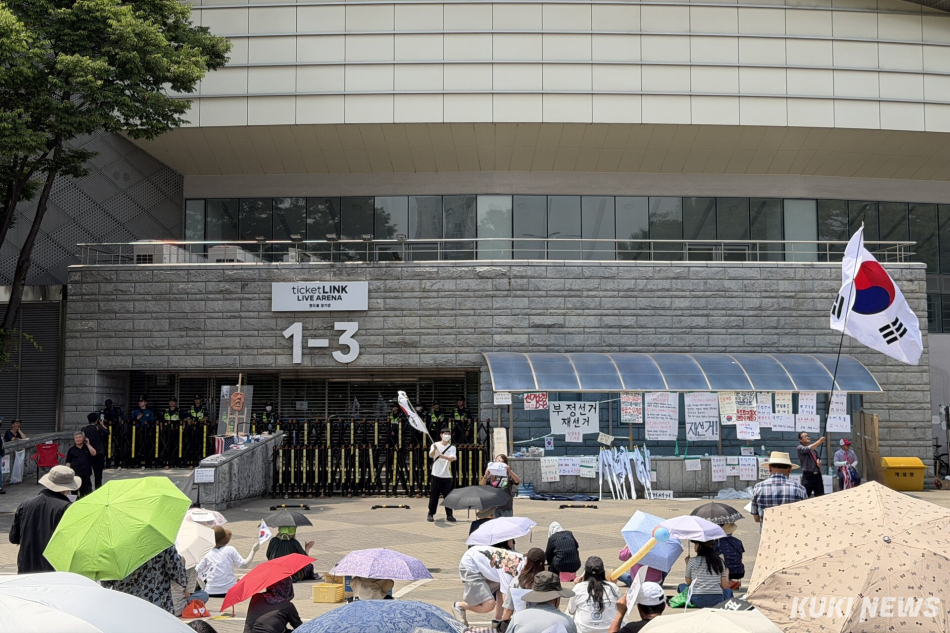 6·3 지방선거 투표용지 부족 사태를 규탄하며 재선거를 요구하는 ‘잠실 개표소 봉쇄 시위’가 계속되고 있는 9일 서울 송파구 올림픽공원 핸드볼경기장 출입구 앞에 시민들이 앉아 투표함 반출을 막고 있다. 유병민 기자