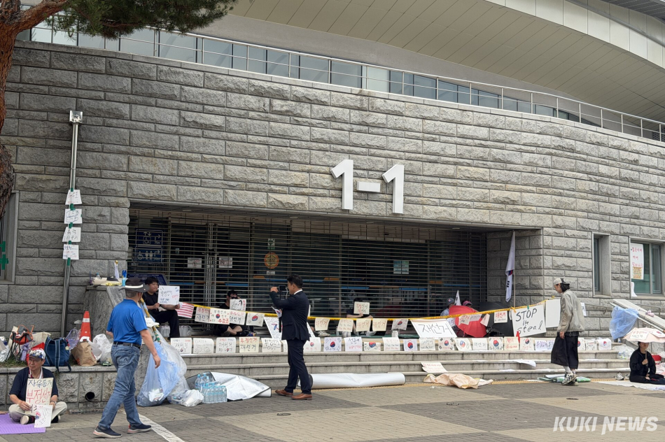 6·3 지방선거 투표용지 부족 사태를 규탄하며 재선거를 요구하는 ‘잠실 개표소 봉쇄 시위’가 계속되고 있는 9일 서울 송파구 올림픽공원 핸드볼경기장 출입구 앞에 시민들이 앉아 투표함 반출을 막고 있다. 유병민 기자