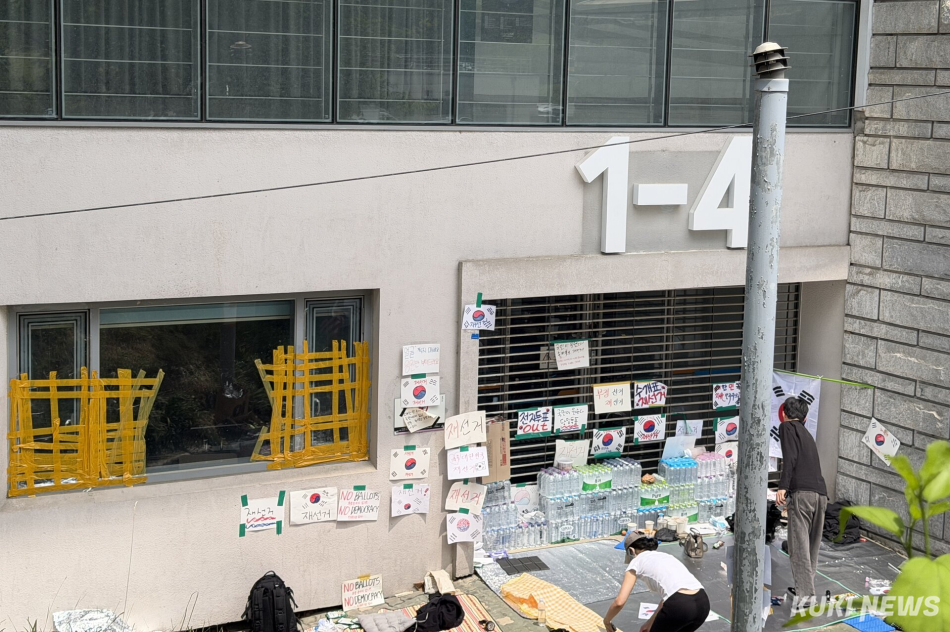 6·3 지방선거 투표용지 부족 사태를 규탄하며 재선거를 요구하는 ‘잠실 개표소 봉쇄 시위’가 계속되고 있는 9일 서울 송파구 올림픽공원 핸드볼경기장 출입구 앞에 시민들이 앉아 투표함 반출을 막고 있다. 유병민 기자