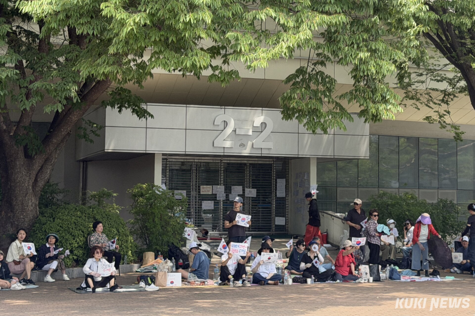 6·3 지방선거 투표용지 부족 사태를 규탄하며 재선거를 요구하는 ‘잠실 개표소 봉쇄 시위’가 계속되고 있는 9일 서울 송파구 올림픽공원 핸드볼경기장 출입구 앞에 시민들이 앉아 투표함 반출을 막고 있다. 유병민 기자