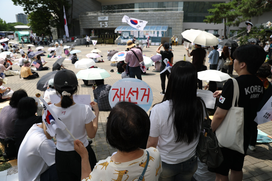 6·3 지방선거 투표용지 부족 사태를 규탄하며 재선거를 요구하는 ‘잠실 개표소 봉쇄 시위’가 계속되고 있는 9일 서울 송파구 올림픽공원 핸드볼경기장에서 시민들이 구호를 외치고 있다. 연합뉴스