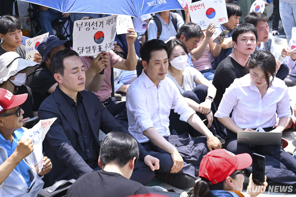 16일 서울 송파구 올림픽공원 핸드볼경기장 앞에 장동혁(가운데 오른쪽) 국민의힘 대표와 김민수 최고위원이 ‘개표소 봉쇄 시위‘ 참가자들과 함께 앉아 있다. 남동균 기자