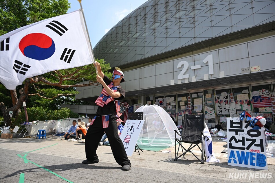 투표용지 부족 사태를 규탄하기 위해 19일 서울 송파구 올림픽공원 핸드볼경기장 앞을 찾은 박경환(32)씨가 대형 태극기를 흔들고 있다. 임은재 기자
