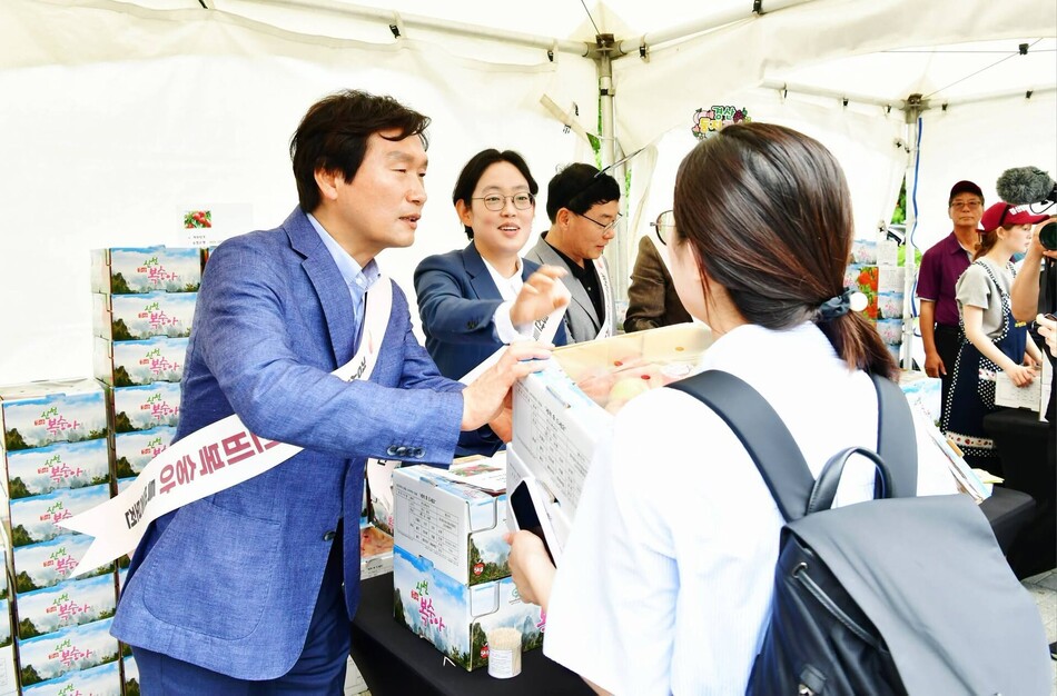 조현일 경산시장과 조지연 의원이 국회 앞 신비복숭아 홍보전에서 복숭아를 건네며 완판 열기를 더하고 있다. 출처=조현일 시장 페이스북