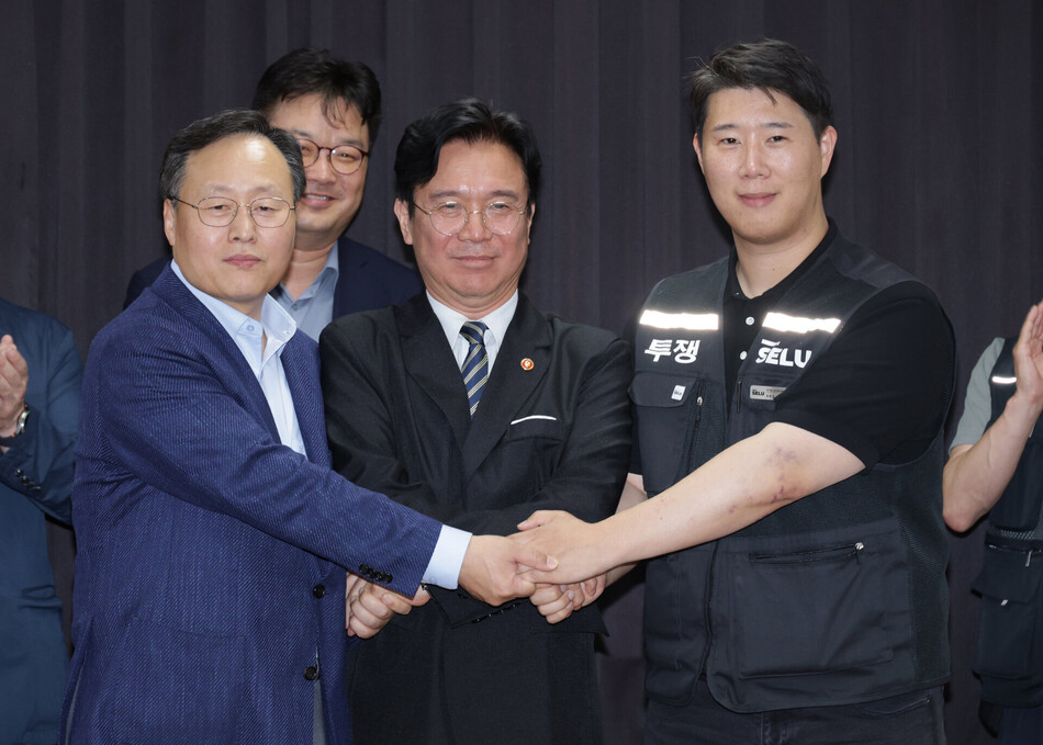 20일 경기도 수원시 장안구 경기고용노동청에서 열린 삼성전자 임금협상을 마친 후 여명구 삼성전자 DS(디바이스솔루션·반도체 사업 담당) 피플팀장과 최승호 삼성그룹 초기업노동조합 삼성전자지부 위원장이 잠정 합의안에 서명한 후 김영훈 고용노동부 장관과 손을 맞잡고 있다. 2공동취재단