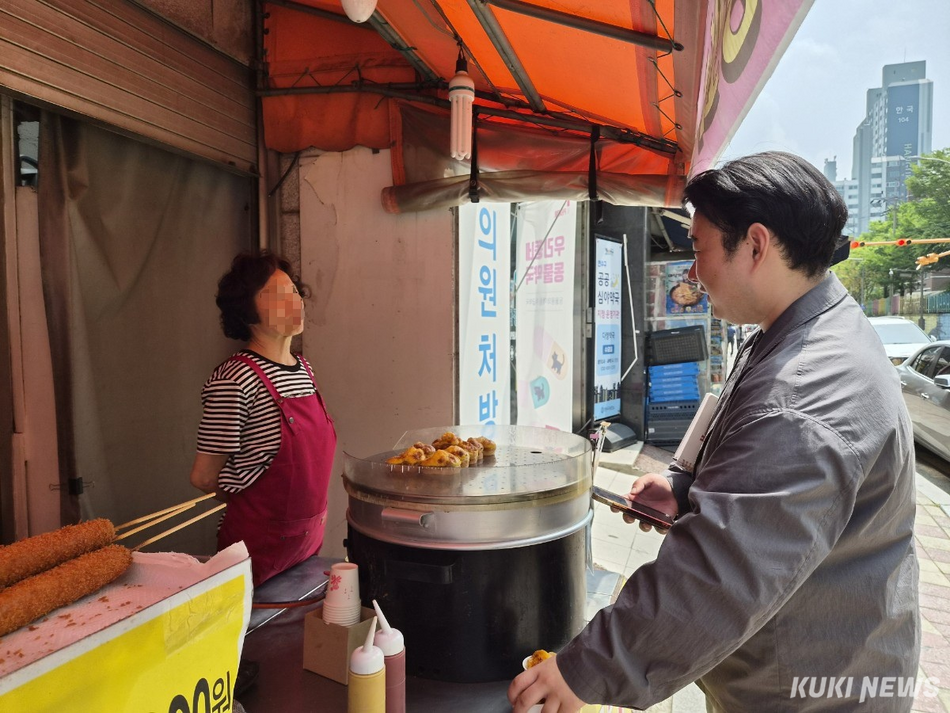 인천 연수구 옥련시장 입구에 있는 핫도그 가게. 변재민씨가 계란빵을 사며 상인에게 안부를 묻고 있다. 선거가 끝난 뒤에도 일주일에 한 번은 동네 상인들에게 인사를 다닌다. 사진=이은서 기자