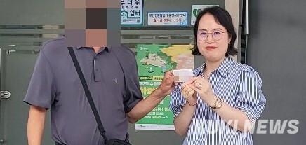 지난 6월 60여 년만에 주민등록증을 발급받은 강 모씨(왼쪽)가 김경숙 베테랑팀장과 주민등록증을 들어 보이며 기뻐하고 있다. 수원시 제공