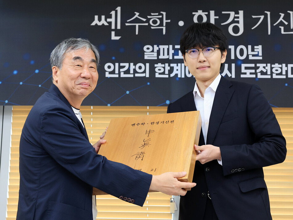 바둑 세계랭킹 1위 신진서 9단이 21일 오후 서울 중림동 한국경제TV 스튜디오에서 열린 ‘쎈수학·한경 기신전(棋神戰)‘ 인공지능(AI) 프로그램 카타고(KataGo)와의 두 점 접바둑 3번기 3국에서 승리를 거둔 후 홍범준 좋은책신사고 대표에게 친필사인 바둑판을 전달하고 있다.